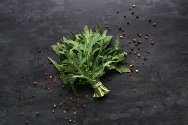 Siyah arka planda taze roka yaprakları ve biberler.