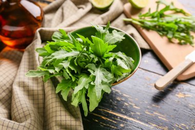Siyah ahşap arka planda taze roka yapraklı kase, yakın plan.