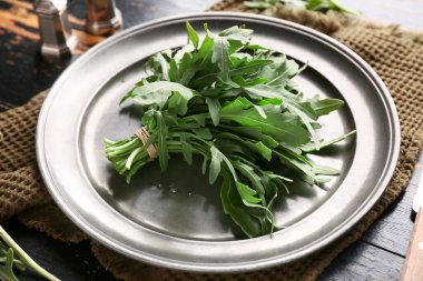 Siyah ahşap arka planda taze roka yapraklarıyla kaplanmış, yakın plan.