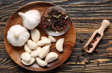 Taze sarımsaklı tabak ve ahşap zemin üzerinde biber.