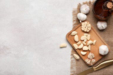 Taze sarımsak karanfilli ahşap tahta ve beyaz arka planda bir sürahi yağ.