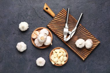 Koyu arkaplanda taze sarımsak ve tahta kaplar.