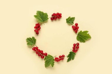 Taze kırmızı üzümlerden yapılmış çerçeve ve sarı arkaplanda yapraklar