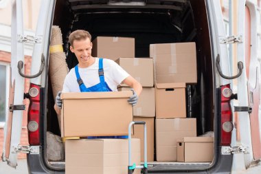 Erkek nakliyeci açık hava vagonunda kutuları boşaltıyor.