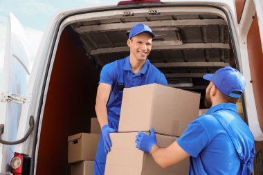 Erkek nakliyeciler sokakta kutuları boşaltıyor.