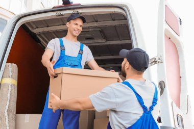 Erkek nakliyeciler dışarıdan kutuları boşaltıyor.