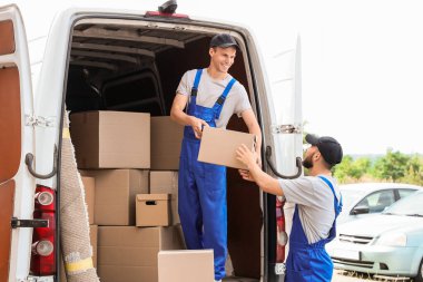 Erkek nakliyeciler dışarıdan kutuları boşaltıyor.