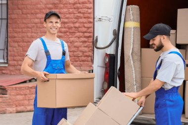 Erkek nakliyeciler açık hava arabasının yakınındaki tramvaya kutuları boşaltıyor.