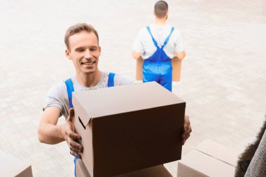 Erkek nakliyeciler açık hava arabasından kutuları boşaltıyor.