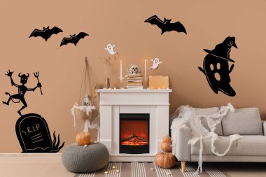 İçinde şömine, gri kanepe ve Cadılar Bayramı süslemeleri olan festival salonu.