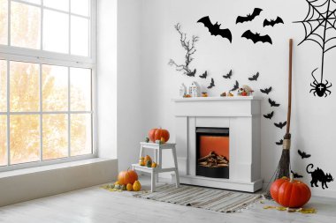 Cadılar Bayramı için dekore edilmiş oturma odasının içi şömine, balkabağı ve kağıt yarasalarla süslenmiş.