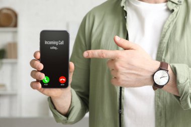 Evdeki boş cep telefonunu gösteren genç adam, yakın plan.