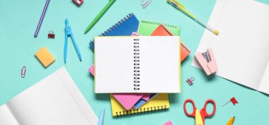 Turkuaz arka planda farklı kırtasiye malzemelerine sahip boş defterler