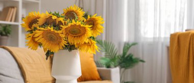 Sehpanın üstünde vazo ve ayçiçekleri olan şık bir oturma odası. Yakın çekim.