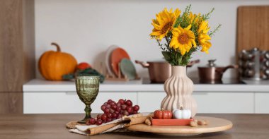 Masada sonbahar çiçekleri, üzümler ve balkabaklarıyla aydınlık mutfağın içi.