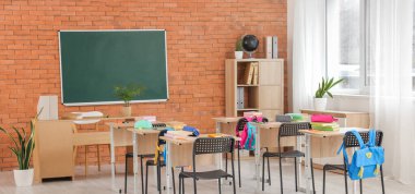 Kara tahta, masa ve sırt çantalı sınıfın içi.