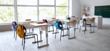 Sıraları, sandalyeleri ve tahtası olan boş sınıfın içi.