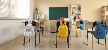 Sıraları ve sandalyeleri olan boş sınıfın içi.