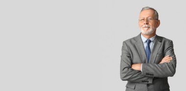 Gri arkaplan ve metin için yeri olan, şık takım elbiseli, olgun bir adam.