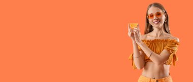 Arka planda taze turuncu dilimi olan güzel genç bir kadın.