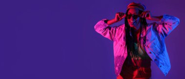 Renkli arka planda dil gösteren örgülü güzel bir Afro-Amerikalı kadın.