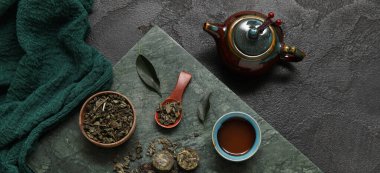 Çaydanlıklı seramik tabak ve siyah zemin üzerinde aromatik puer çayı.