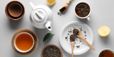 Beyaz arka planda çay demliği, kase ve kuru çay yapraklı kompozisyon