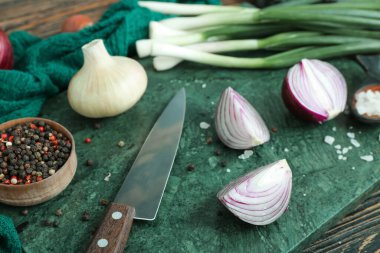 Kahverengi ahşap arka planda farklı soğan ve baharat çeşitleri olan tahta.