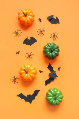 Turuncu arka planda balkabakları, kağıt yarasalar ve örümceklerle kompozisyon. Cadılar Bayramı konsepti