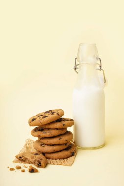 Çikolatalı kurabiyeler ve sarı arka planda bir şişe süt.