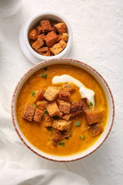 Beyaz arka planda kızarmış ekmeklerle bir kase lezzetli krema çorbası.