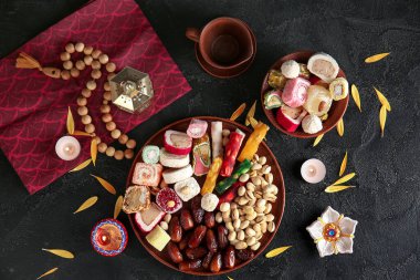 Siyah zemin üzerinde mumlar, boncuklar ve farklı tabaklar bulunan Diya lambaları. Divaly kutlaması