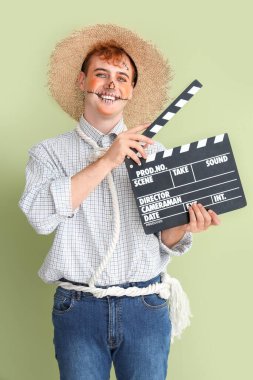 Cadılar Bayramı için yeşil arka planda el çırpmalı korkuluk gibi giyinmiş yakışıklı genç adam.