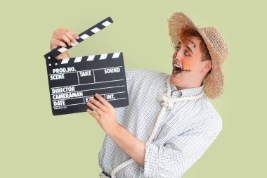 Cadılar Bayramı için yeşil arka planda el çırpmalı korkuluk gibi giyinmiş yakışıklı genç adam.