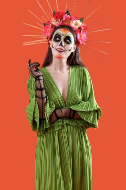 Cadılar Bayramı için turuncu arka planda giyinmiş düşünceli genç bir kadın.