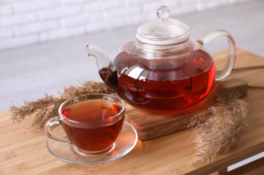 Ahşap masada şeffaf çay ve çaydanlık.