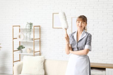 Oturma odasında el temizleyicisiyle gülümseyen hizmetçi.