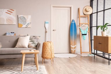 Gri kanepe ve sörf tahtasıyla modern oturma odasının içinde.