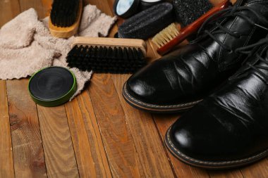 Ahşap arka planda parlak ayakkabılar ve ayakkabı temizleme araçları