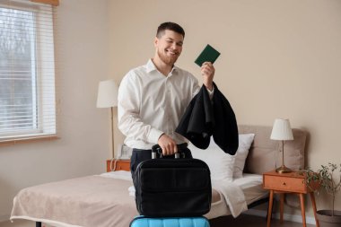 Otel odasında pasaportu ve çantası olan mutlu bir işadamı.