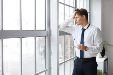 Ofisteki pencerenin yanında baş ağrısı çeken genç bir işadamı