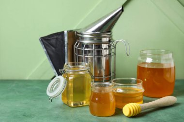 Kavanozlar ve bir bardak tatlı bal ve yeşil grunge arka planda dipper.