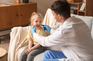 Erkek çocuk doktoru küçük kızı muayene ediyor.