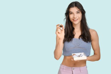 Mavi arka planda bir kutu çikolatalı şekerlemesi olan güzel genç bir kadın.