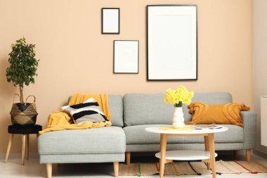 Oturma odasında rahat bir kanepe, sehpa ve vazo çiçekleri var.