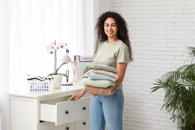 Güzel bir Afro-Amerikalı kadın evde temiz giysiler giyiyor.