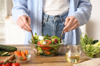 Genç bayan mutfakta taze sebze salatası hazırlıyor.