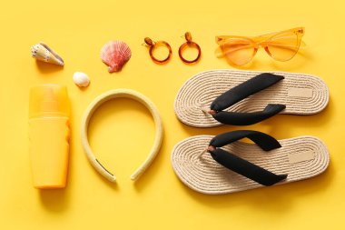 Turuncu arka planda plaj aksesuarları ve güneş kremi olan güzel bir kompozisyon.