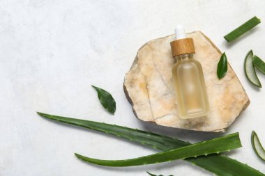 Taş, taze aloe yaprakları ve arka planda gerekli yağ şişesi.