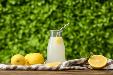 Dışarıdaki ahşap masada naneli bir şişe limonata.